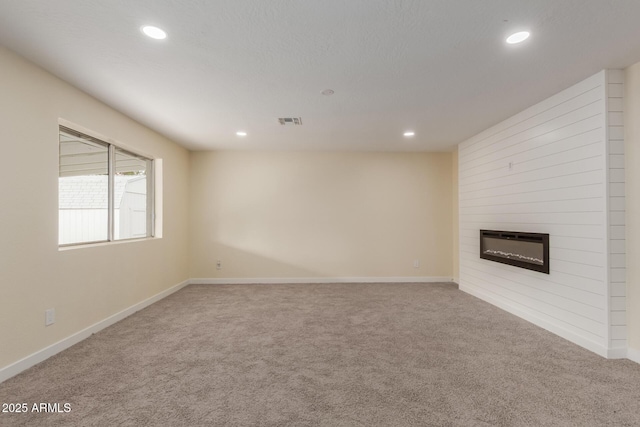 unfurnished living room featuring visible vents, recessed lighting, a fireplace, and carpet floors