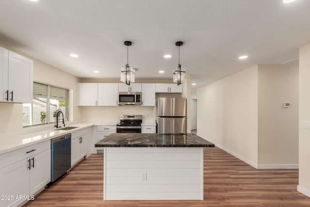 kitchen with white cabinetry, wood finished floors, appliances with stainless steel finishes, and a kitchen island