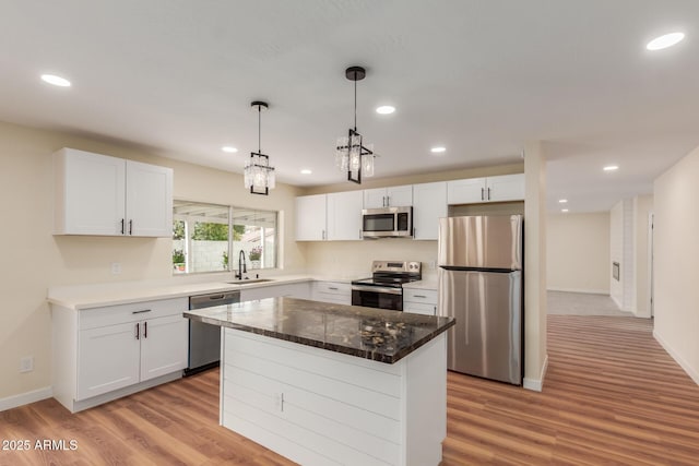 kitchen with a sink, light wood-style floors, appliances with stainless steel finishes, and white cabinetry