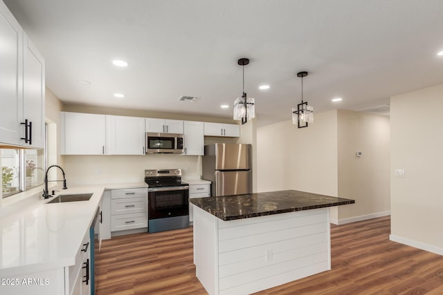 kitchen with a sink, visible vents, appliances with stainless steel finishes, and wood finished floors