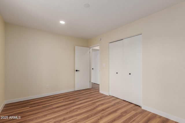 unfurnished bedroom featuring light wood-style flooring, recessed lighting, baseboards, and a closet