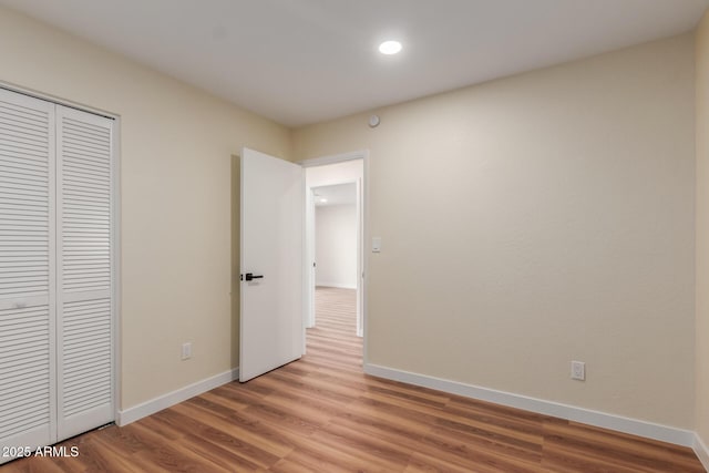 unfurnished bedroom with baseboards, light wood-type flooring, and a closet