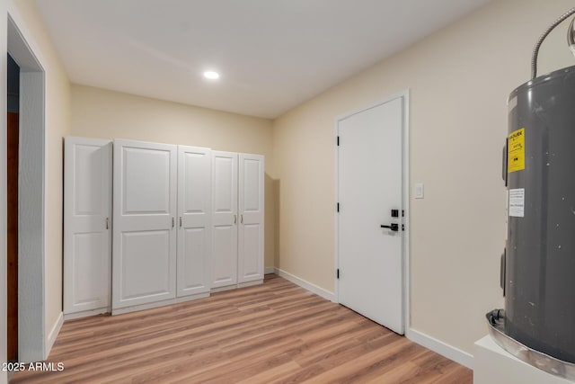 interior space with light wood-style flooring, recessed lighting, baseboards, and electric water heater