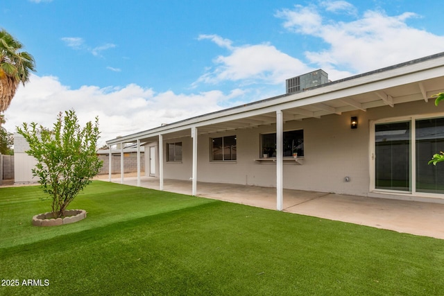 rear view of property featuring concrete block siding, a patio, a lawn, and central AC