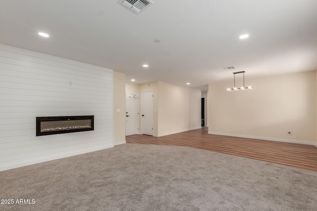 unfurnished living room with visible vents, recessed lighting, a large fireplace, and carpet floors