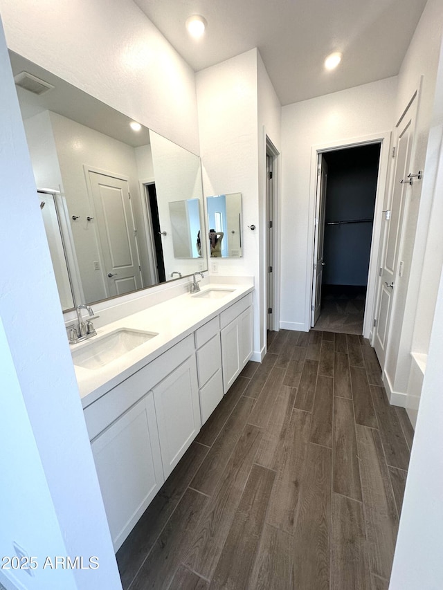 bathroom featuring double vanity, wood tiled floor, baseboards, and a sink