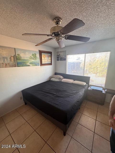 bedroom featuring light tile patterned floors, a textured ceiling, and ceiling fan