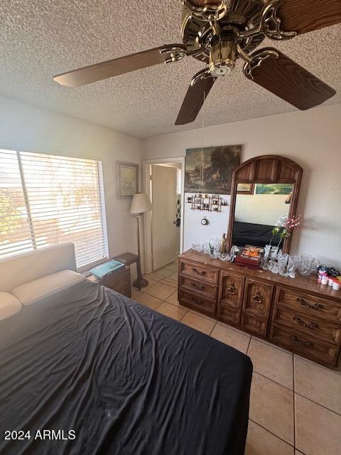 tiled bedroom with a textured ceiling and ceiling fan