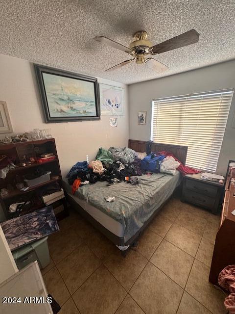 tiled bedroom with ceiling fan and a textured ceiling