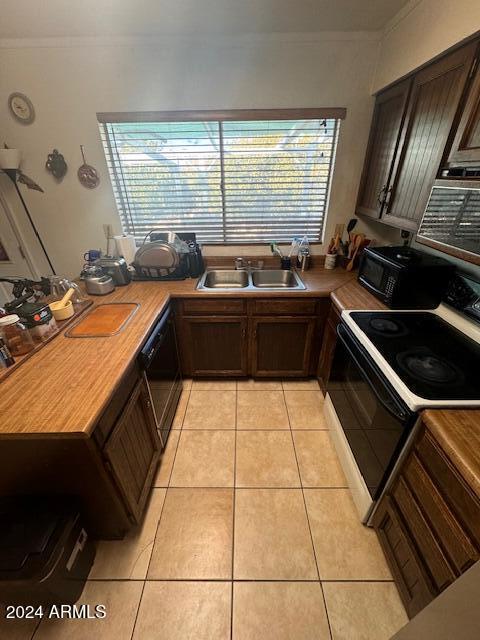 kitchen featuring white range with electric cooktop, light tile patterned floors, a healthy amount of sunlight, and black dishwasher