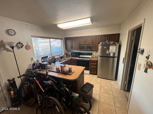 kitchen featuring dark brown cabinets, a textured ceiling, stainless steel appliances, sink, and light tile patterned floors