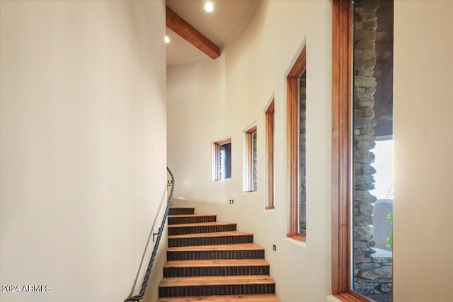 stairs featuring a high ceiling and beam ceiling