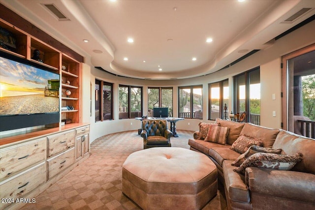 carpeted living room with built in features, a raised ceiling, and a healthy amount of sunlight