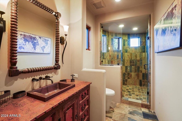 bathroom with vanity, toilet, and a shower with door