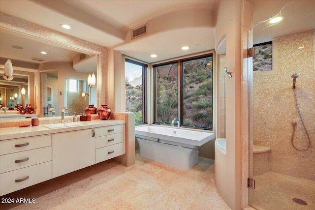 bathroom with a wealth of natural light, independent shower and bath, tile flooring, and large vanity