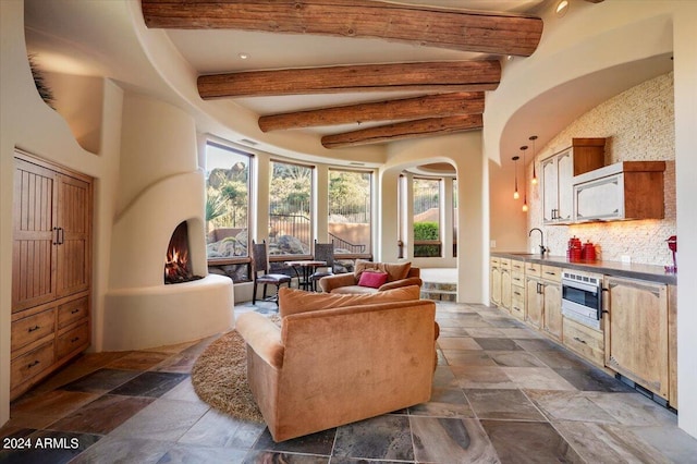 living room with dark tile flooring, beam ceiling, and sink