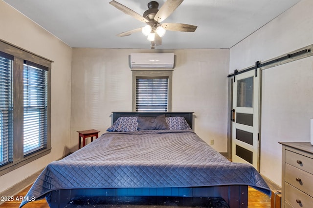 816 Tombstone Cyn Unit C, Bisbee, AZ 85603 - bedroom featuring a wall mounted AC, a barn door, ceiling fan, and wood finished floors