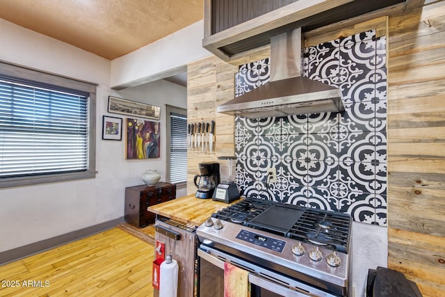 816 Tombstone Cyn Unit C, Bisbee, AZ 85603 - kitchen with stainless steel gas range, wall chimney exhaust hood, hardwood / wood-style floors, wooden walls, and a textured ceiling