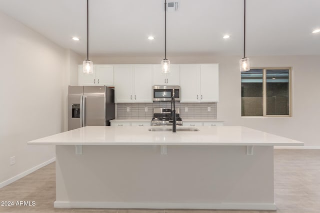 kitchen featuring pendant lighting, stainless steel appliances, and a kitchen island with sink