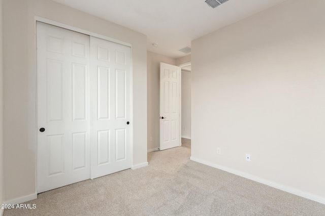 unfurnished bedroom featuring light colored carpet and a closet