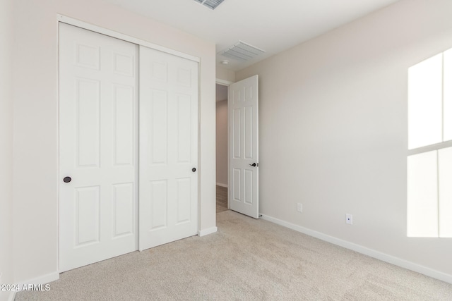 unfurnished bedroom featuring light carpet and a closet