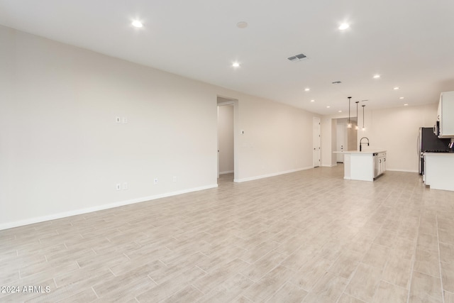 unfurnished living room featuring light hardwood / wood-style flooring and sink