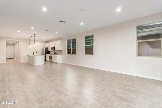 unfurnished living room featuring sink and light hardwood / wood-style flooring