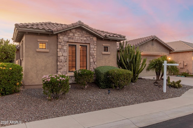 20558 N 263rd Dr, Buckeye, AZ 85396 - view of front of house featuring driveway, a tile roof, a garage, stone siding, and stucco siding
