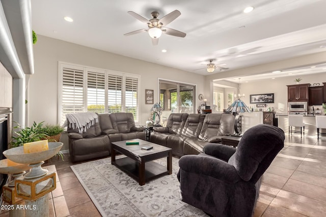 living area with light tile patterned floors, ceiling fan with notable chandelier, and recessed lighting