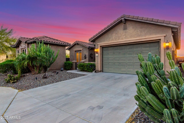 ranch-style house with a garage, stucco siding, concrete driveway, and a tile roof