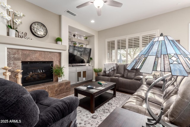 living area featuring visible vents, recessed lighting, ceiling fan, and a tile fireplace