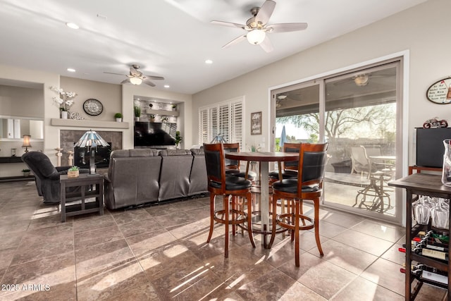dining space with recessed lighting, a ceiling fan, and a glass covered fireplace