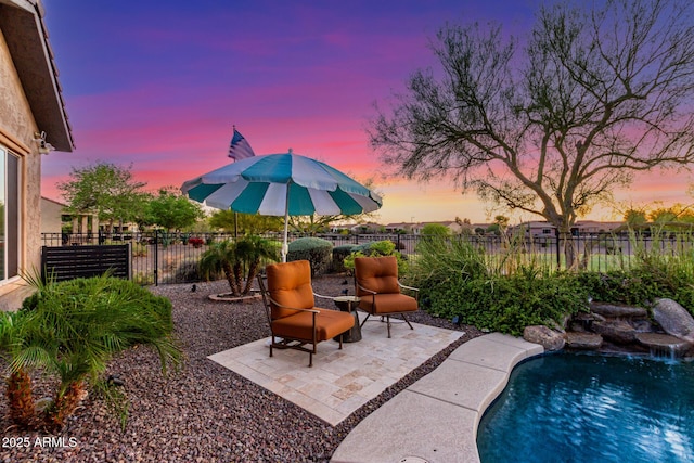 pool at dusk with a fenced backyard, a fenced in pool, and a patio