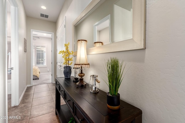 corridor with visible vents, baseboards, and tile patterned flooring