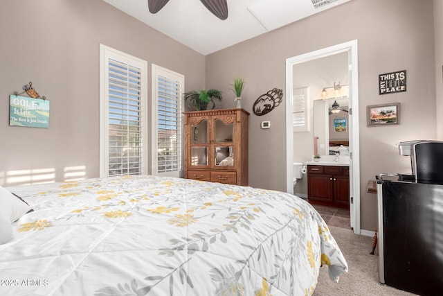 bedroom featuring light carpet, a ceiling fan, and connected bathroom