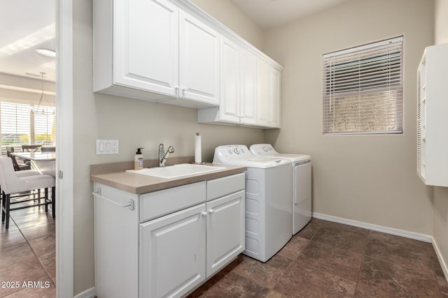 clothes washing area with a sink, baseboards, cabinet space, and washer and dryer