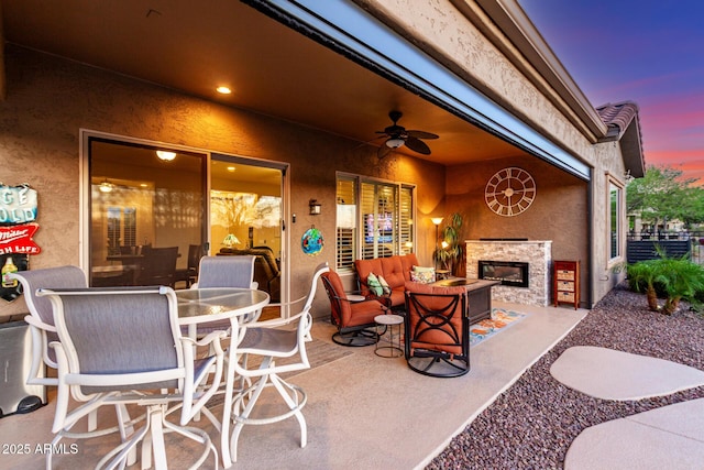 view of patio / terrace featuring ceiling fan and an outdoor stone fireplace