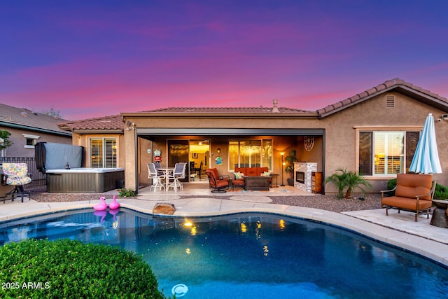 back of property at dusk with fence, a patio, stucco siding, an outdoor living space, and a hot tub