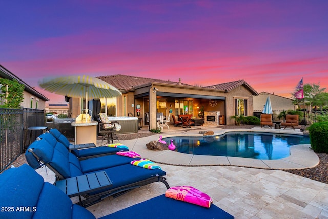 pool at dusk with outdoor dry bar, a fenced in pool, a fenced backyard, a patio, and outdoor lounge area