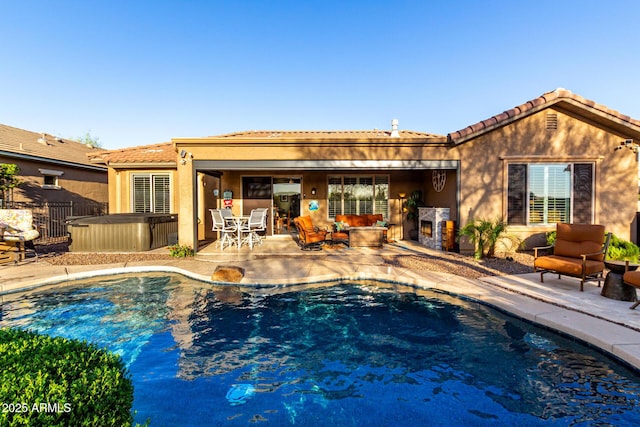 rear view of property featuring a patio, a hot tub, stucco siding, and a tile roof