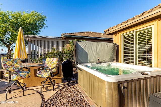 view of patio with a hot tub and fence