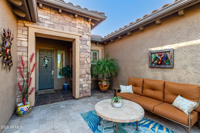 doorway to property with a patio, stucco siding, stone siding, and an outdoor hangout area