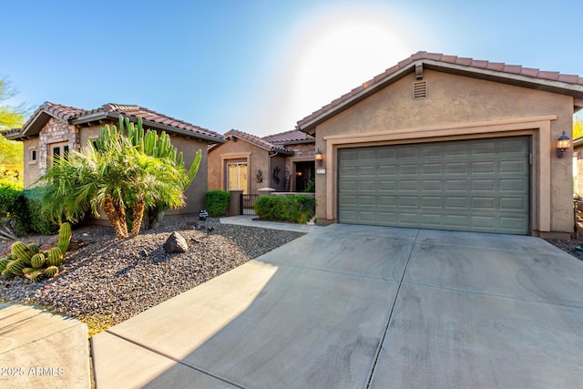 mediterranean / spanish home with an attached garage, stucco siding, a tile roof, and concrete driveway