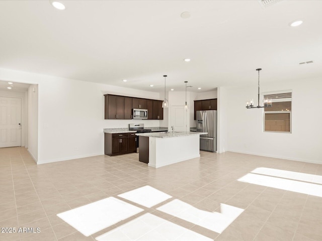 kitchen with sink, an inviting chandelier, appliances with stainless steel finishes, an island with sink, and pendant lighting