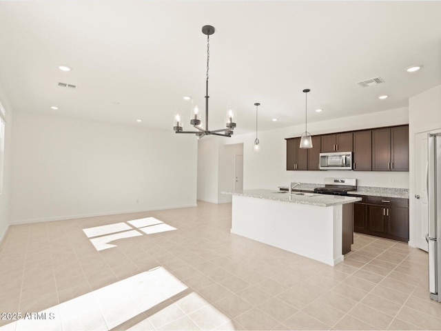 kitchen with dark brown cabinetry, sink, hanging light fixtures, appliances with stainless steel finishes, and light stone countertops