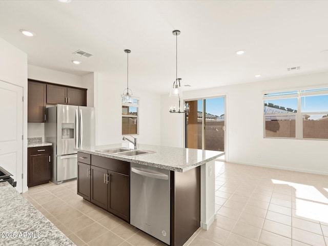 kitchen featuring sink, hanging light fixtures, dark brown cabinets, stainless steel appliances, and an island with sink