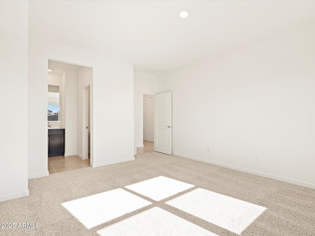 unfurnished bedroom featuring connected bathroom and light carpet