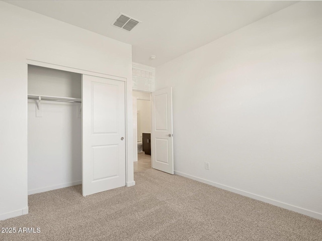 unfurnished bedroom with light colored carpet and a closet