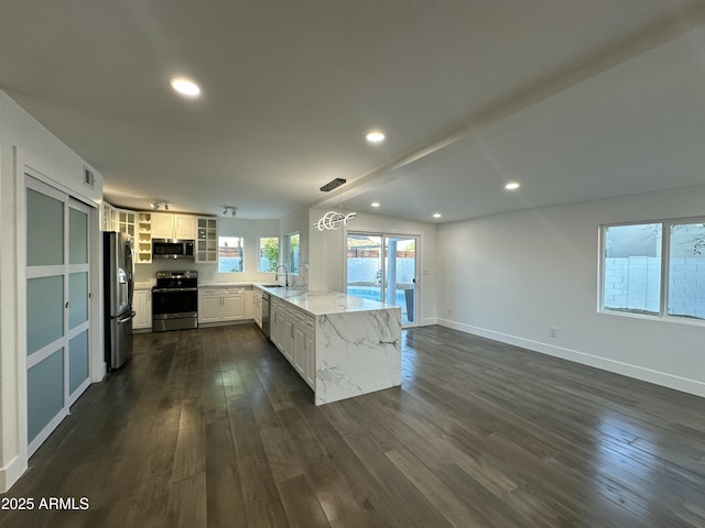 kitchen with decorative light fixtures, kitchen peninsula, appliances with stainless steel finishes, dark wood-type flooring, and white cabinets