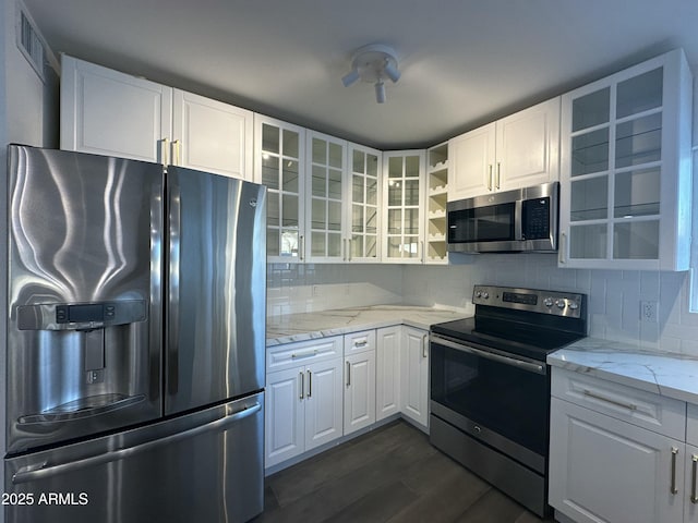 kitchen featuring white cabinets, dark hardwood / wood-style flooring, stainless steel appliances, decorative backsplash, and light stone counters